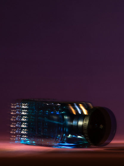 ANFAS SAMA — flacone blu disteso in luce viola; fotografia ufficiale ANFAS