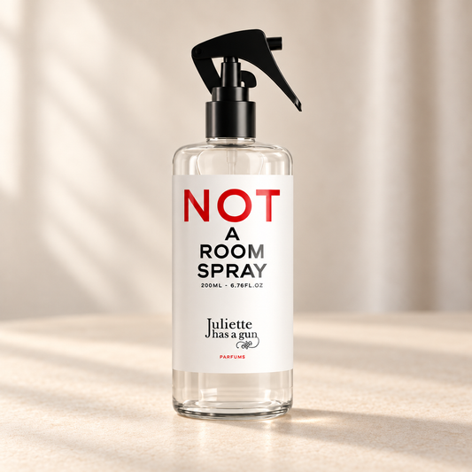NOT A ROOM SPRAY di Juliette Has a Gun — prodotto su fondo beige, ambientazione creata con IA